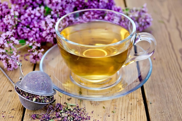 Tisane d'origan avec passoire dans une tasse en verre