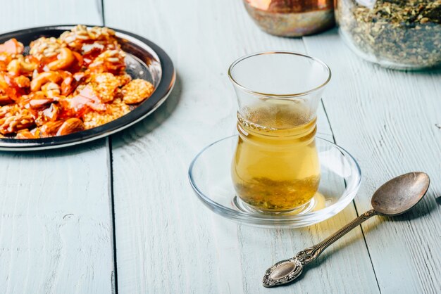 Tisane en verre armudu avec délices de noix orientales sur plaque de métal sur une surface en bois clair