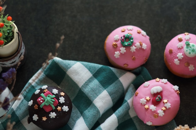 Un tissu à carreaux vert et blanc a trois cupcakes avec un glaçage rose et un arc blanc et or.