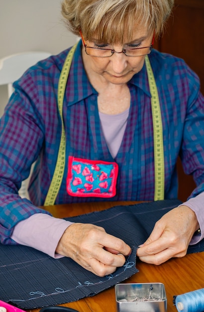 Tissu de couture de couturière senior pour fabriquer un vêtement dans son atelier