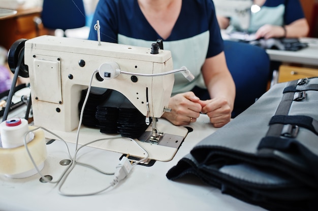 Tissu de couture de mains féminines sur une machine de fabrication professionnelle sur le lieu de travail. Processus de couture.