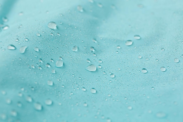 Tissu imperméable turquoise avec des gouttes d'eau en gros plan d'arrière-plan