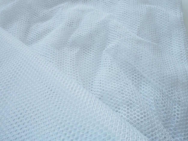 Le tissu en maille de tulle netlike blanc transparent est froissé ou plié négligemment en voile bleu blanc ou en mousseline