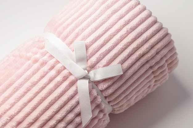 Tissu molletonné rose pastel doux avec des lignes qui s'enroulent comme cadeau avec un fond blanc en ruban en gros plan