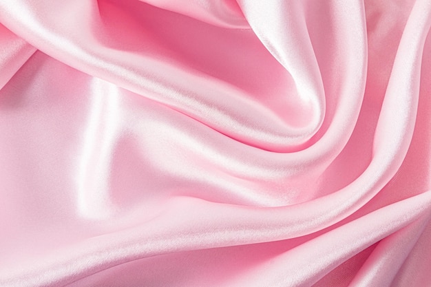 Tissu satiné élégant de couleur rose La texture luxueuse des plis doux du tissu Le concept d'un fond festif