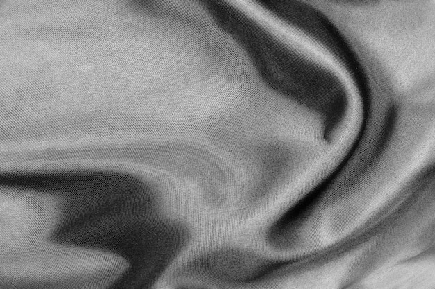 Un tissu de soie noir élégant et lisse ou une texture de tissu de luxe en satin peut être utilisé comme arrière-plan de mariage pour un design abstrait luxueux de draperie