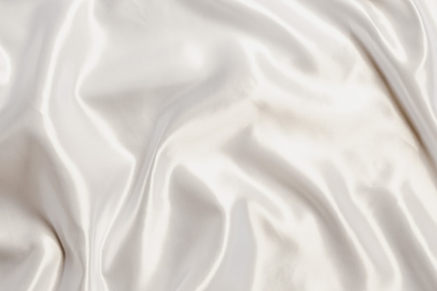 Tissu soyeux en satin blanc abstrait pour le fond, drapé en tissu avec plis ondulés. avec des vagues douces, ondulant dans le vent.