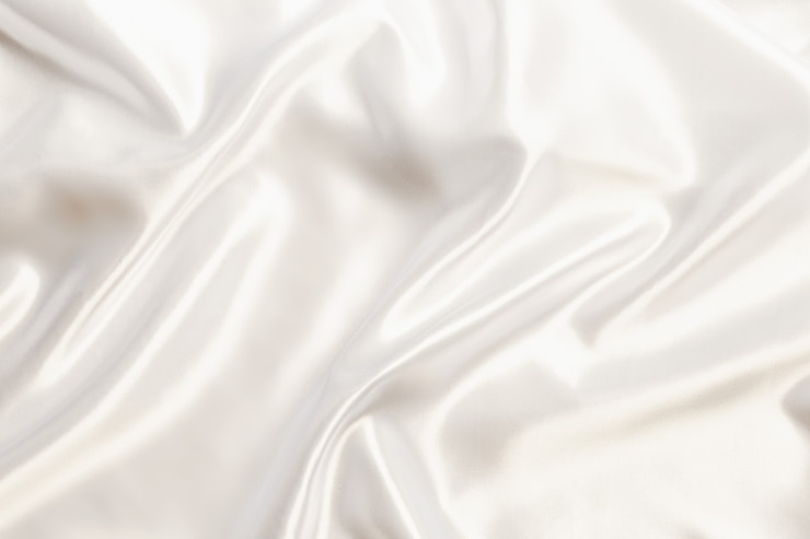Photo tissu soyeux en satin blanc abstrait pour le fond, drapé en tissu avec plis ondulés. avec des vagues douces, ondulant dans le vent.