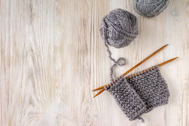 Tissu tricoté sur des aiguilles à tricoter en bois et des pelotes de laine sur un espace de copie de fond en bois blanc