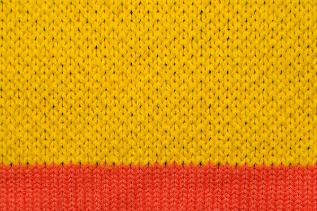 Tissu tricoté synthétique jaune et rouge se bouchent. Texture de tissu tricoté. Contexte