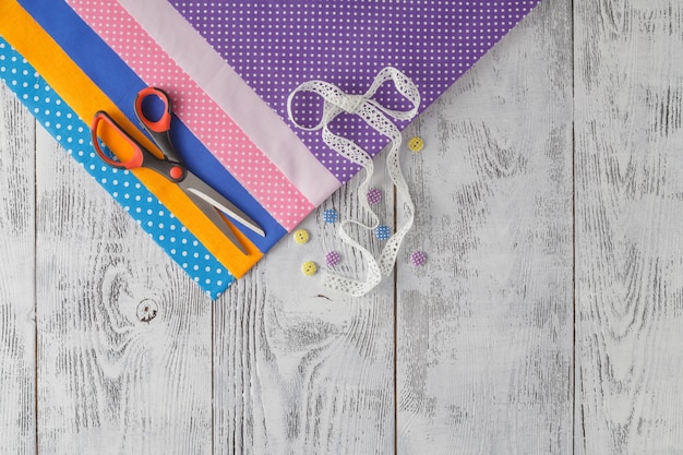 Tissus en coton à coudre, dentelles et accessoires pour travaux d'aiguille sur fond de bois.