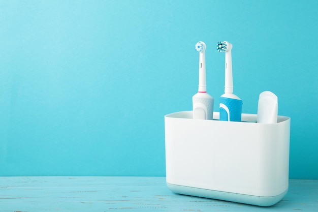 Titulaire avec brosses à dents électriques modernes sur fond bleu