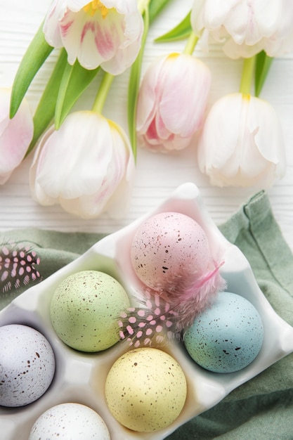 Titulaire avec des oeufs de Pâques peints en couleurs pastel sur un fond en bois blanc