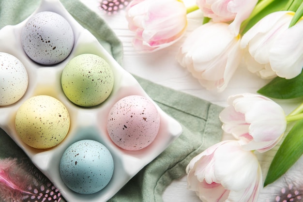 Titulaire avec des oeufs de Pâques peints en couleurs pastel sur un fond en bois blanc