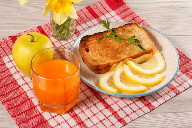 Toast au beurre et fromage tranches de citron sur assiette pomme bouquet de jonquilles jaunes