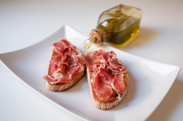 Toast au jambon et à l'huile à côté d'une bouteille d'huile Petit-déjeuner traditionnel d'Espagne