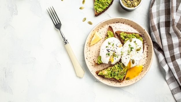 Toast aux œufs pochés avec avocat sur pain de seigle bannière menu recette place pour texte vue de dessus