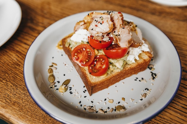 Toast à l'avocat avec du poulet placé sur une table en bois.