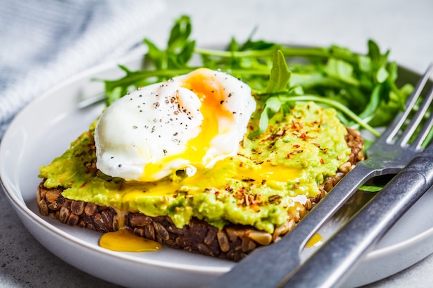 Toast à l'avocat avec œuf poché sur une assiette grise. Concept d'aliments sains végétariens.