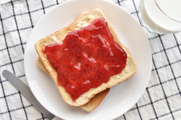 Toast avec confiture de fraises et beurre sur une assiette blanche