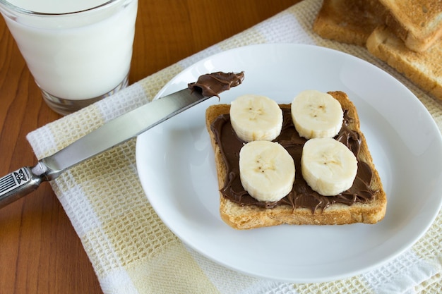 Toast avec crème au chocolatbanane et lait sur la table