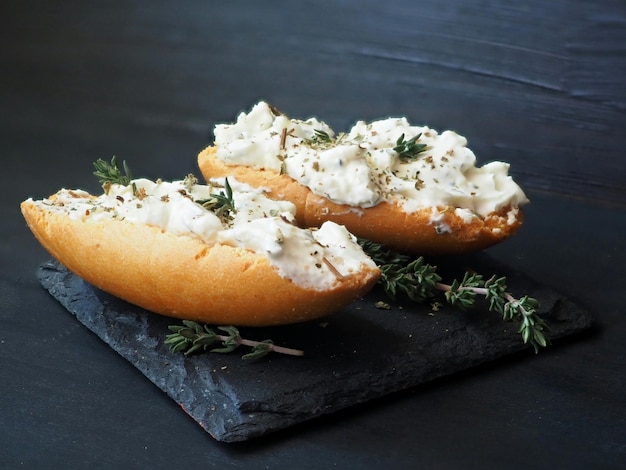 Toast avec du fromage blanc et des herbes isolé sur fond noir