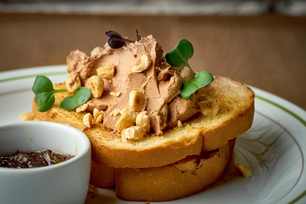 Toast avec du pâté et des noix dans une assiette sur un fond en bois