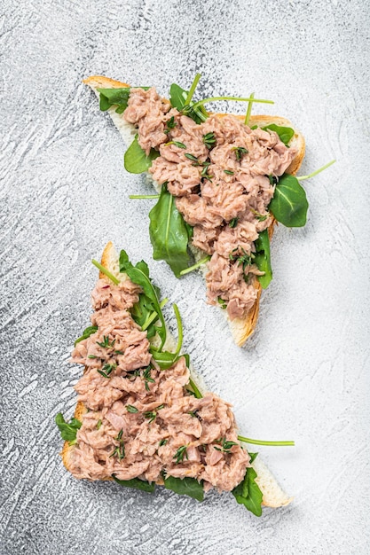 Toast avec du thon en conserve et de la roquette. Fond blanc. Vue de dessus.