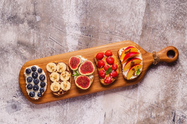 Toast d'été fait maison avec beurre de noix de fromage à la crème et vue de dessus de fruits et baies