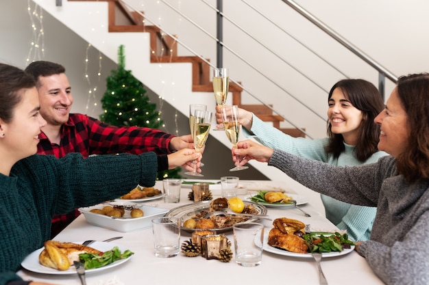 Toast familial souriant avec champagne célébrant le dîner de Noël ensemble à la maison