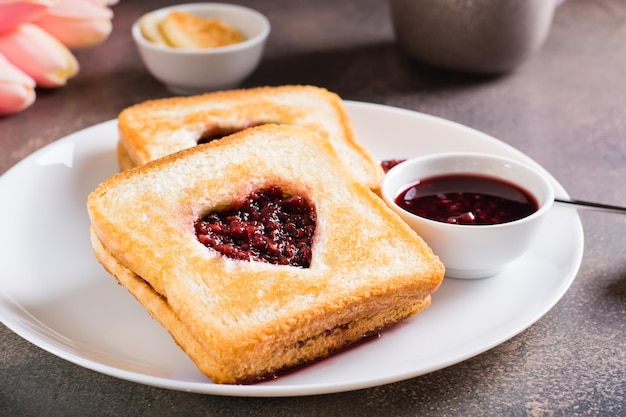 Toast en forme de coeur avec de la confiture de framboises sur une assiette Nourriture pour les amoureux