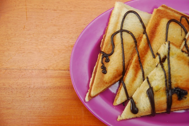 Toast avec garniture au chocolat servi sur une table en bois