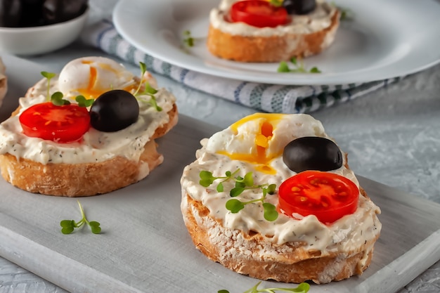 Toast de pain croustillant fait maison avec tomate, œuf poché et olive. Une collation rapide à base de bonne nourriture
