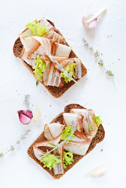 Toast de pain de seigle avec tranches de bacon (pancetta, saindoux), ail et herbes italiennes, antipasti, bruschetta italienne (crostini)