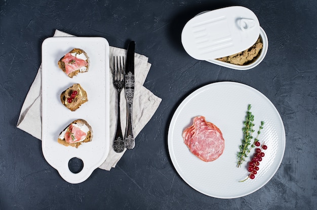 Toast avec Parme, salami et pâté d&#39;oie sur une planche à découper blanche