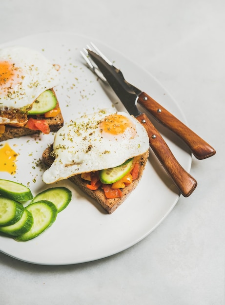 Toast de petit-déjeuner avec légumes et oeuf au plat sur plaque blanche