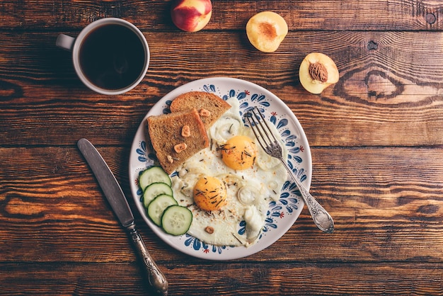 Toast de petit-déjeuner avec des œufs au plat avec des légumes, des fruits et du café