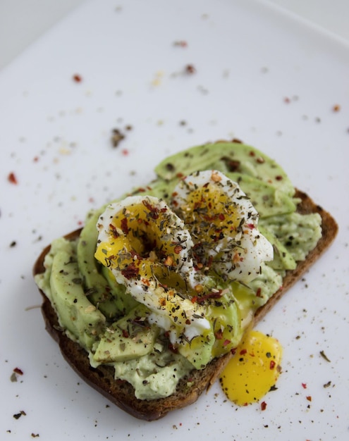 Toast végétarien avec avocat et œuf et épices sur une image de gros plan de plaque blanche avec mise au point sélectionnée