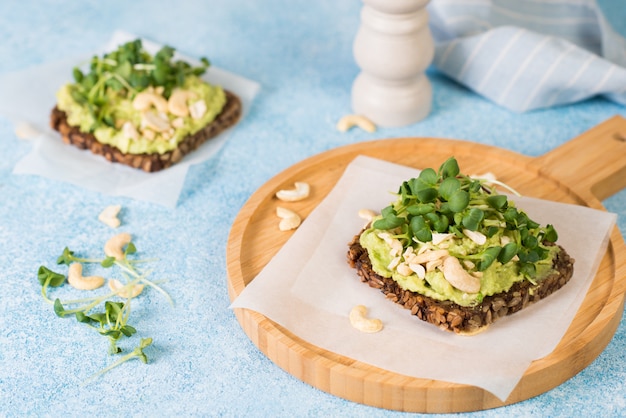 Toast vert végétalien avec pâte d'avocat, noix et micro-légumes