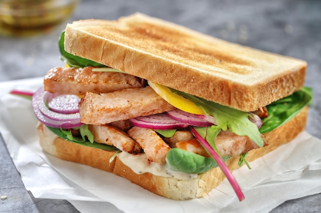 Toasts appétissants avec morceaux de poulet et salade sur table.