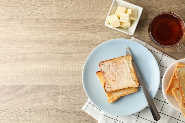 Toasts sur assiette, serviette, thé et beurre sur fond de bois, espace copie