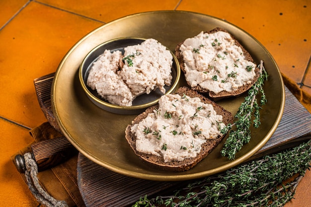 Toasts au foie de morue Pâte à tartiner sur une assiette Fond orange Vue de dessus