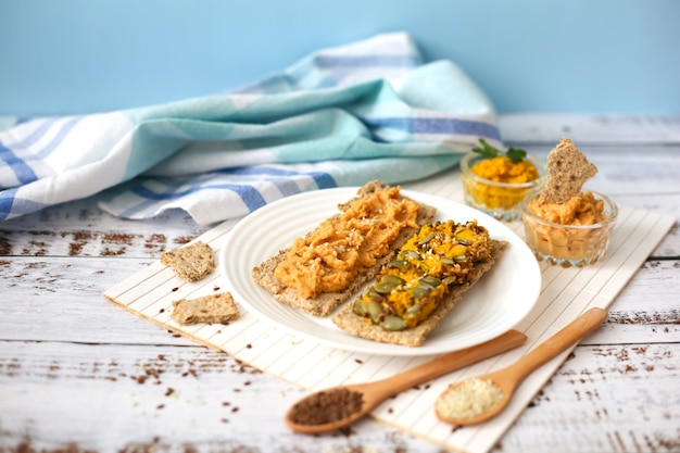 Toasts au houmous sur fond de bois blanc. Pâte de pois chiches sur des craquelins. Concept de nourriture végétarienne