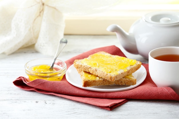 Toasts au miel sur assiette et tasse de thé sur fond clair