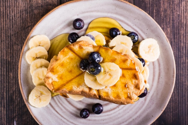 Toasts aux myrtilles et au miel à la banane sur une assiette Dessert maison Gros plan sur la vue de dessus