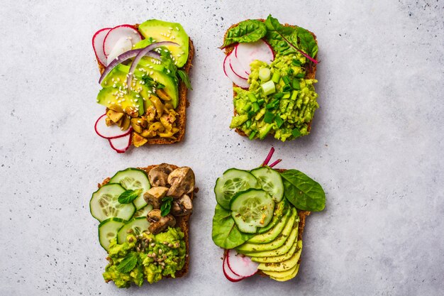 Toasts d&#39;avocat avec différentes garnitures, vue de dessus, fond blanc.