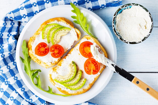 Toasts à l'avocat avec du fromage à la crème sur une serviette blanc-bleu