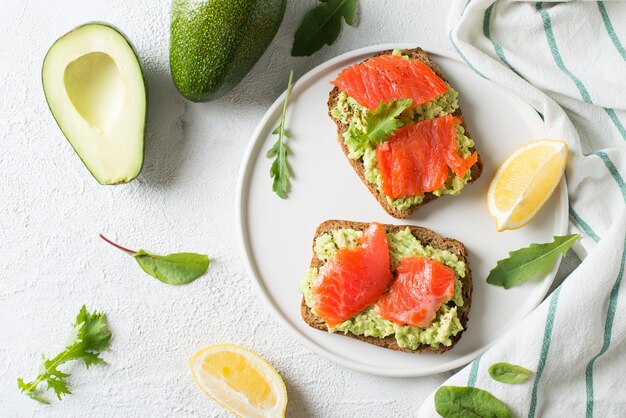 Toasts à l'avocat et saumon sur plaque sur fond blanc