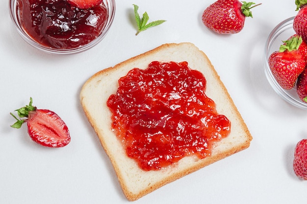 Toasts avec confiture de fraises pour le petit déjeuner sur fond de bois rustique blanc Vue de dessus