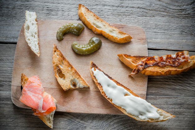 Toasts avec différentes garnitures sur la planche de bois